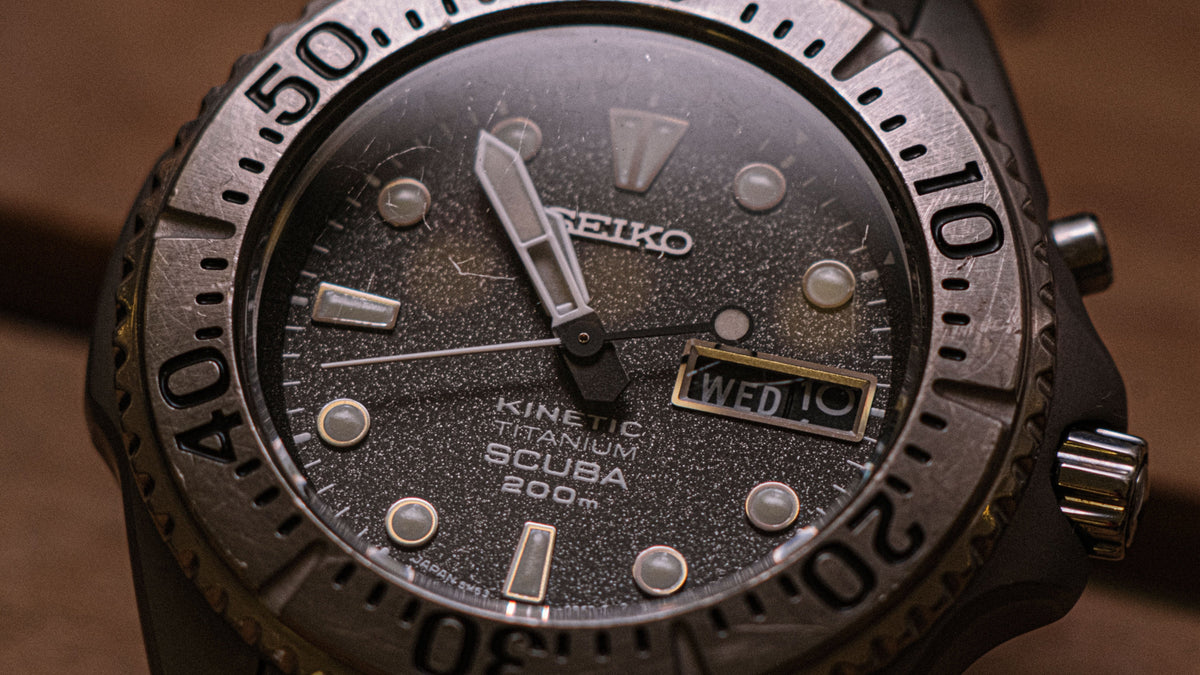 Gros plan macro d'une montre de plongée Seiko au boîtier en titane brossé et cadran texturé indiquant le mercredi.