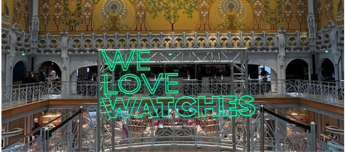 Enseigne néon « We Love Watches » sous la verrière historique de La Samaritaine à Paris lors du salon horloger.