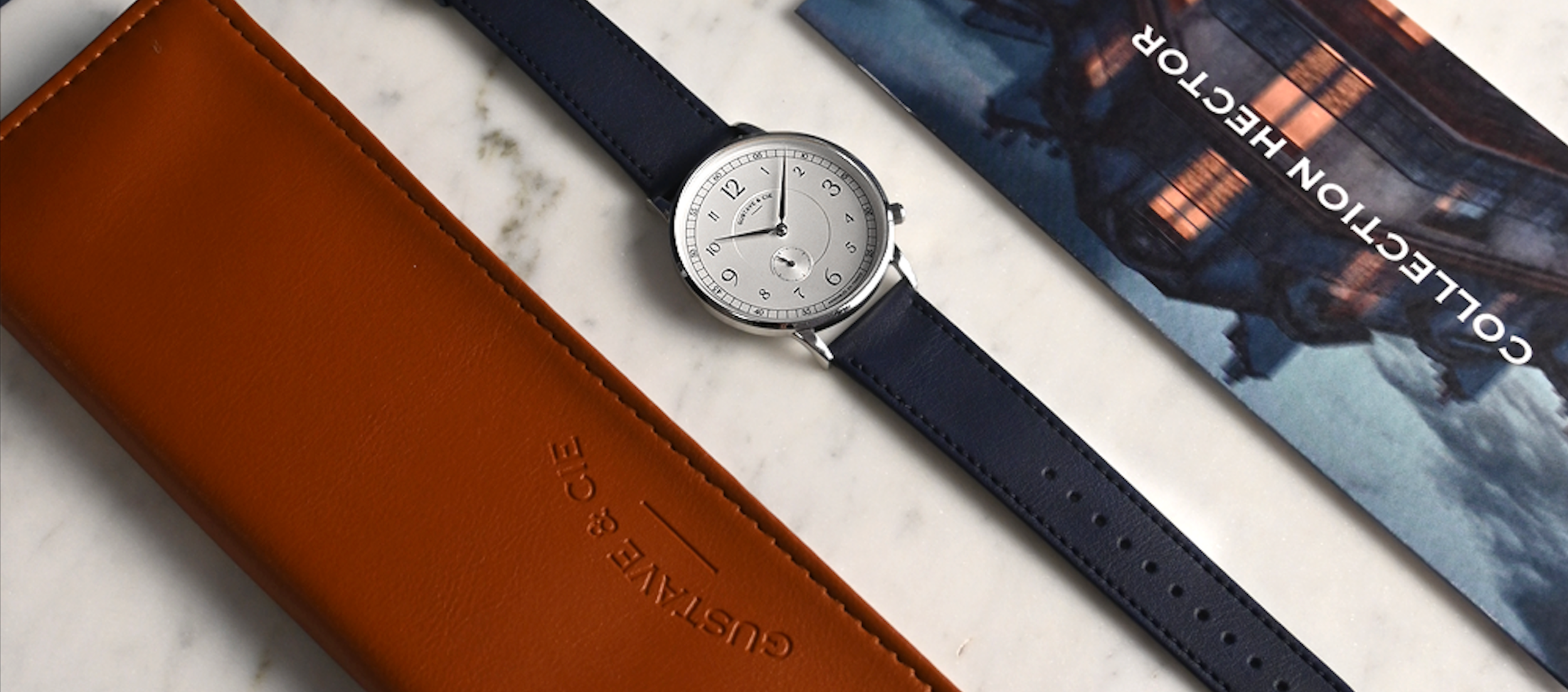 Présentation du packaging Gustave & Cie avec pochette en cuir, montre et documentation de la marque