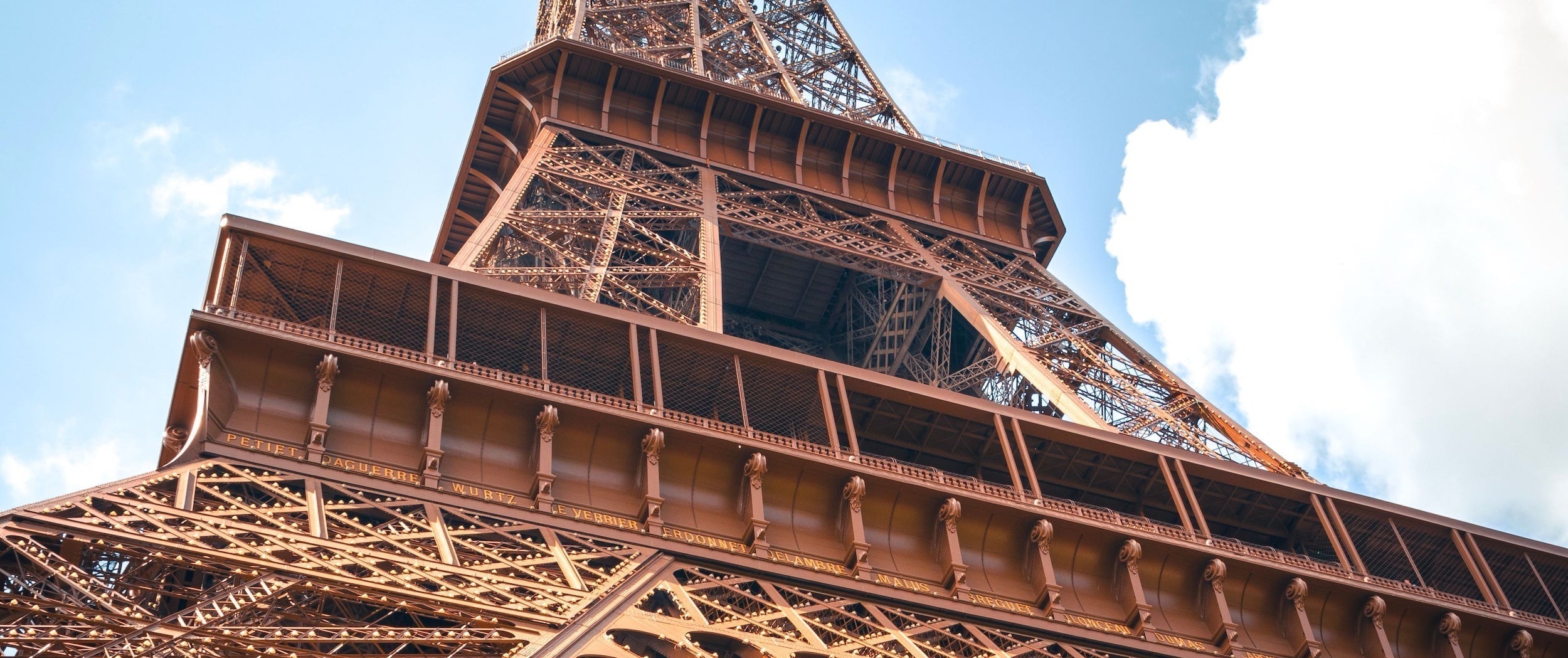 Vue en contre-plongée de la Tour Eiffel, mettant en valeur le premier et le deuxième étage ainsi que la structure métallique emblématique du monument.